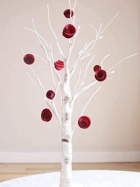 A white birch tree with red roses on top.