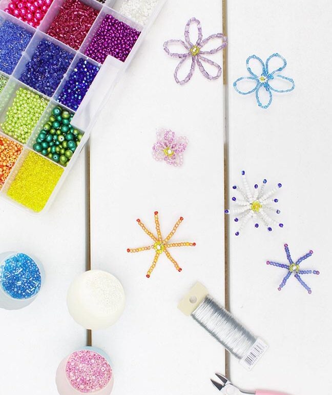 A table with beads, scissors, and a beading kit.