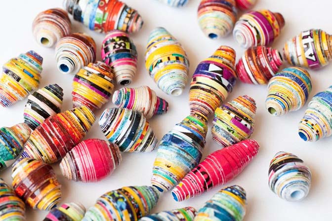 A group of colorful paper beads on a white surface.