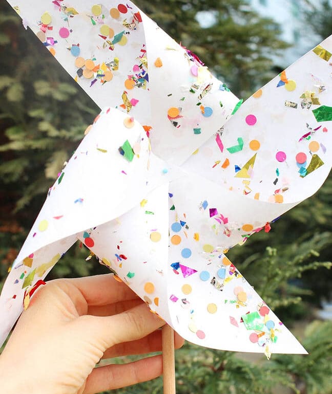 A person holding a paper pinwheel with confetti on it.