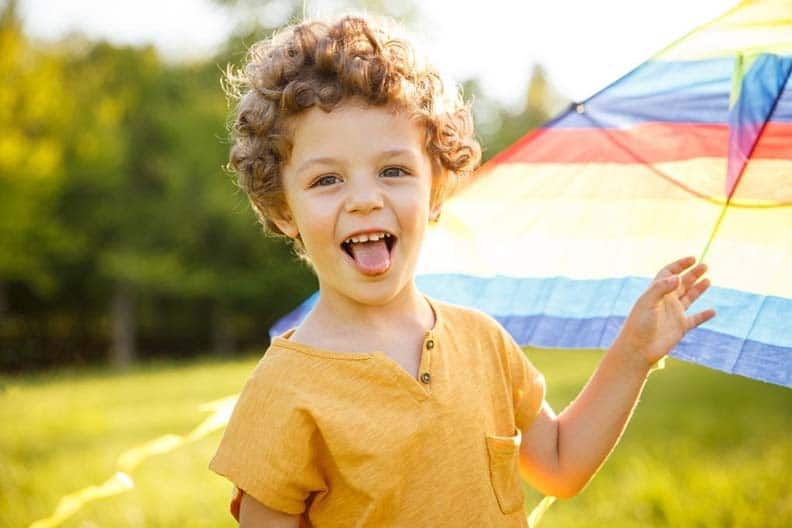 A young boy is playing with a kite in a field.