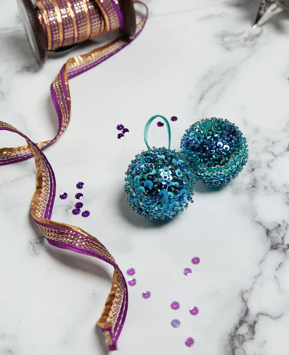 Two blue and purple glitter ornaments on a marble table.