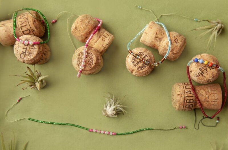 A group of wine corks with beaded bracelets and air plants.
