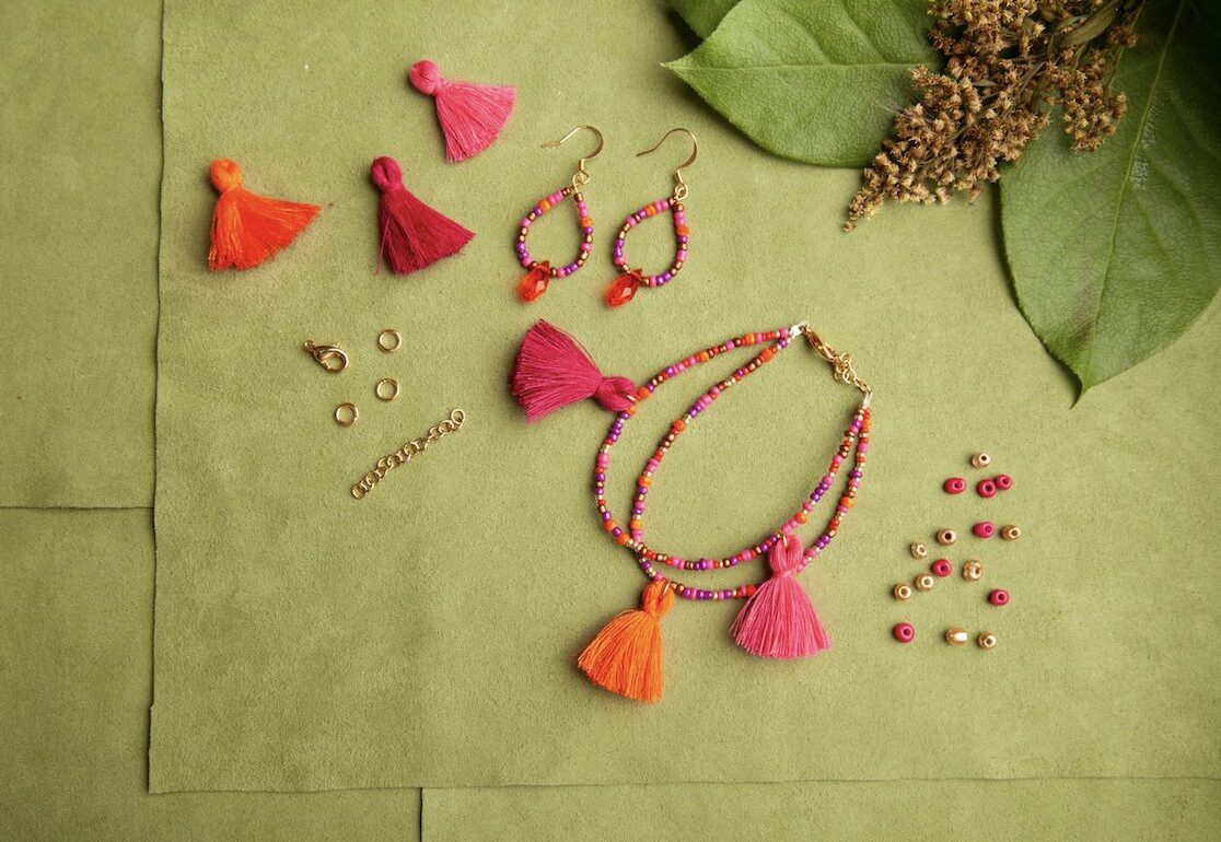 Tassels, beads, and other jewelry are laid out on a green leaf.