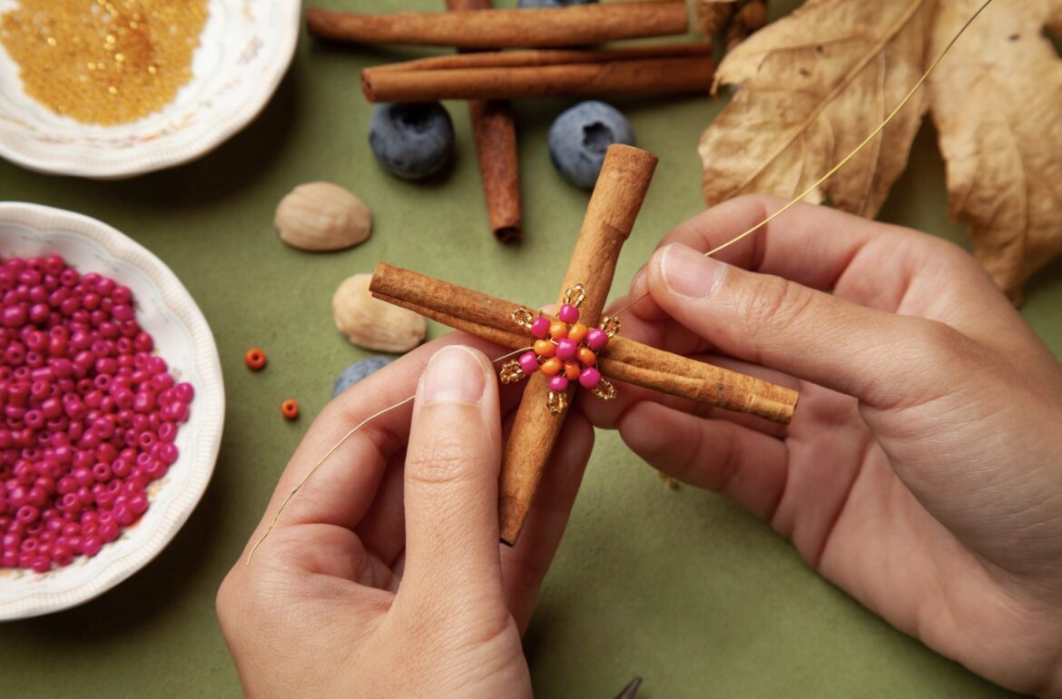 A woman is making a cross with cinnamon sticks and beads.