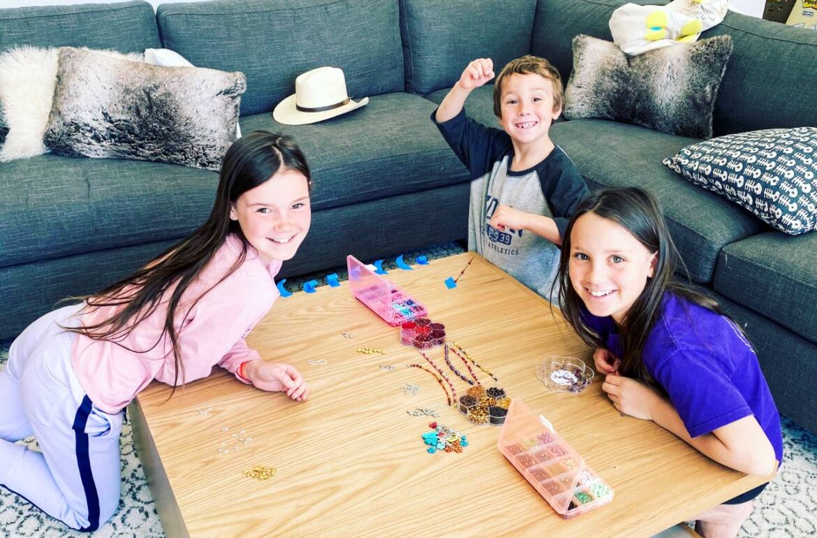 Three kids playing a game on a table in a living room.