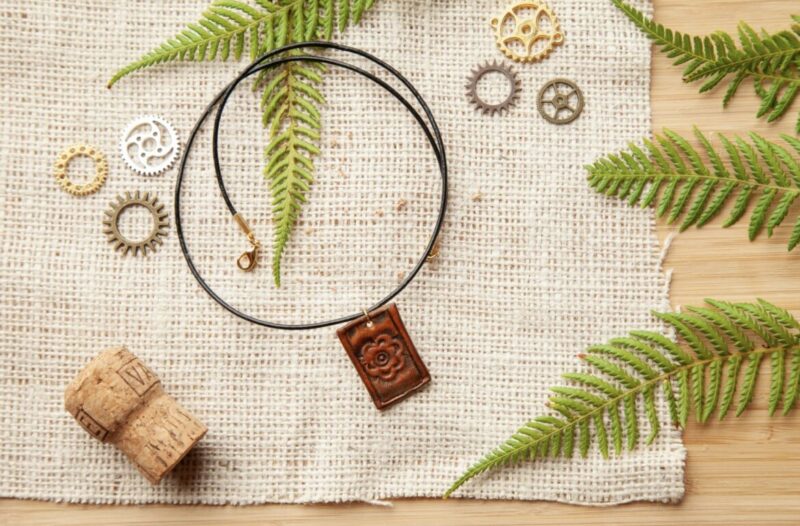 A brown leather necklace with gears and fern leaves.