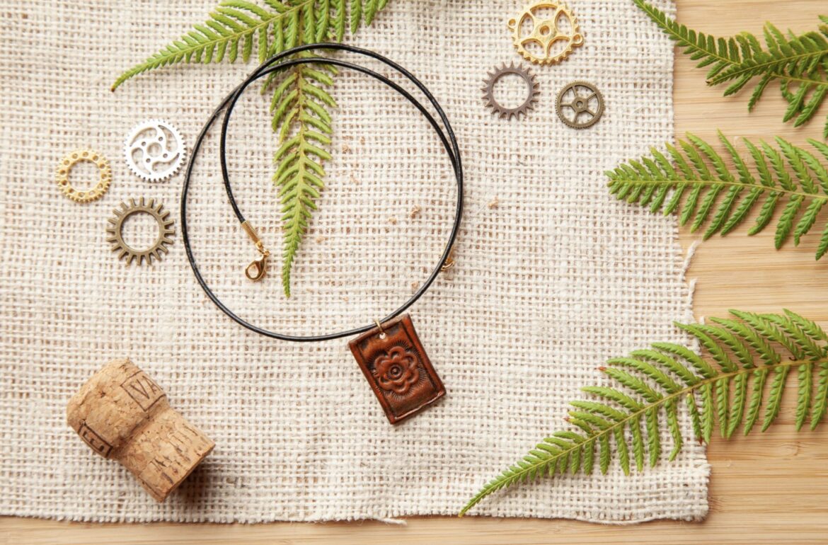 A brown leather necklace with gears and fern leaves.