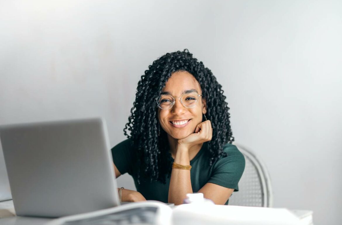 A young african american woman sitting at a desk with a laptop.