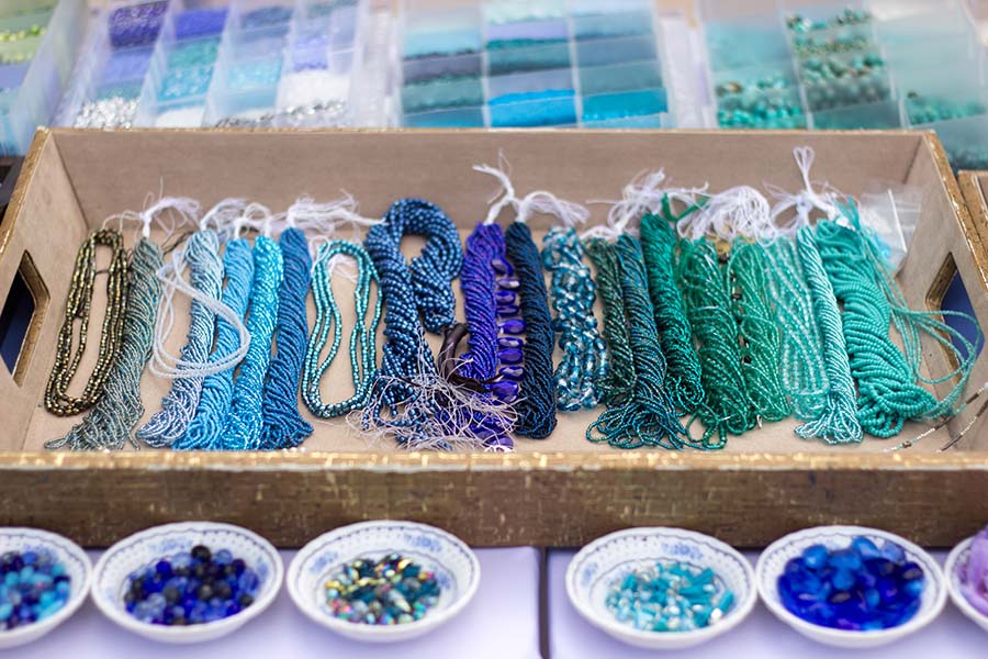 A display of blue and green beads in a wooden box.