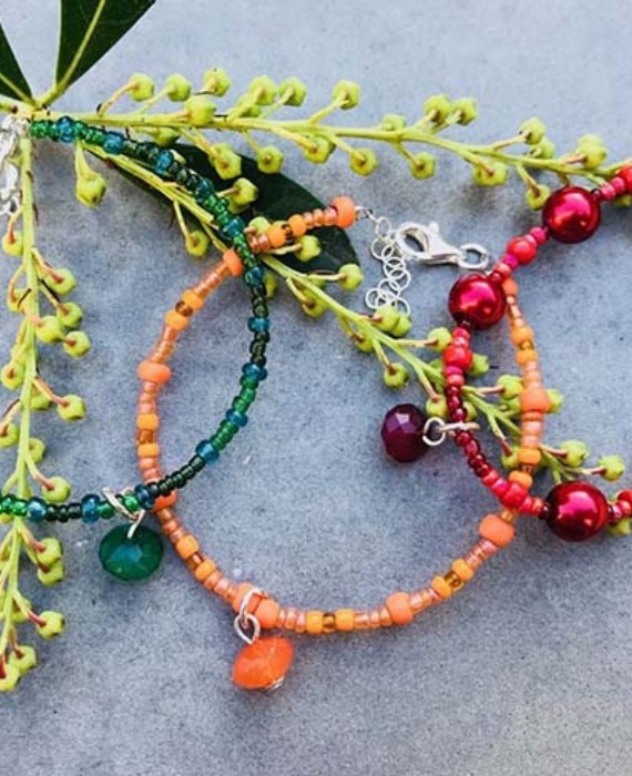 Three beaded bracelets with red, orange and green beads.