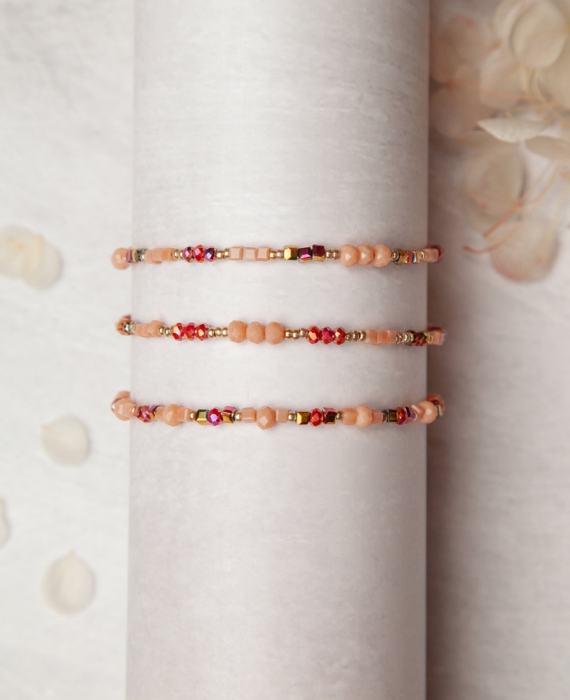 A set of three pink beaded bracelets on a white background.