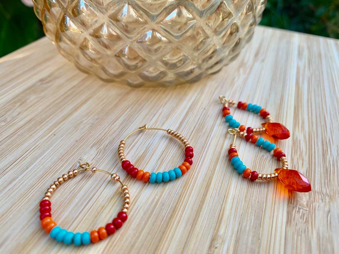 Three colorful hoop earrings on a wooden table.