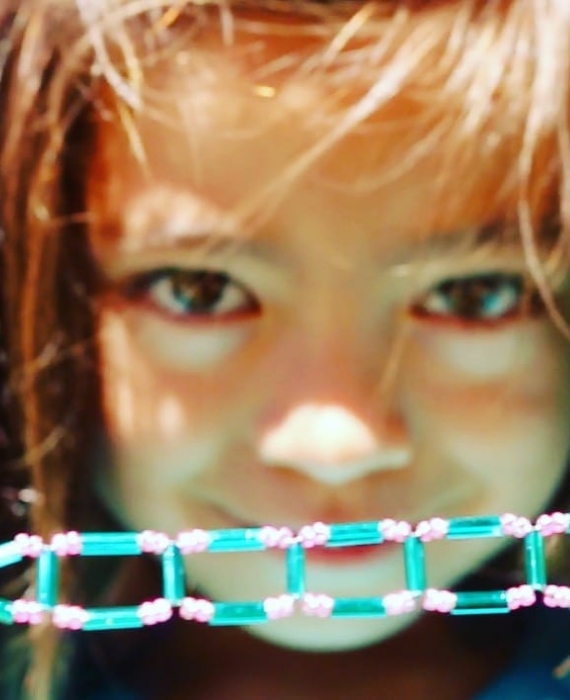 A young girl is holding a string of beads.