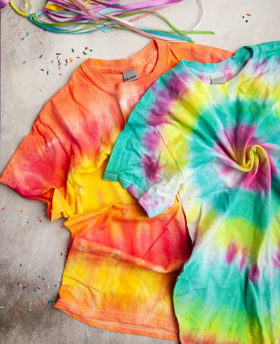 Two tie dye t - shirts on a table.