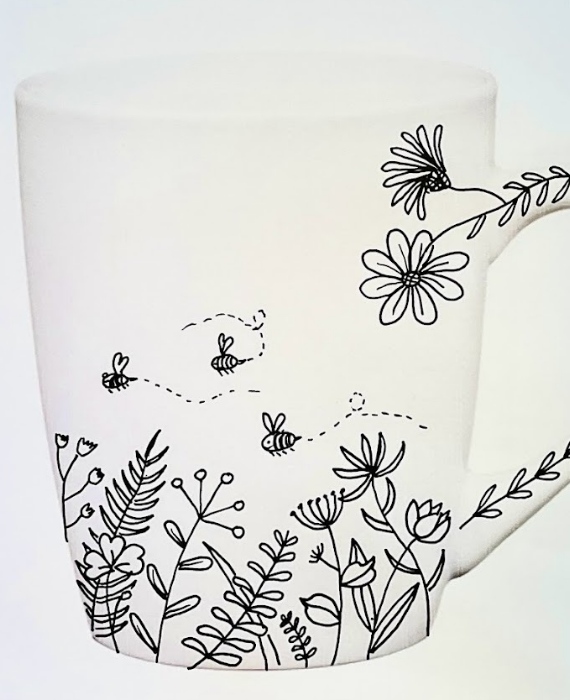 A black and white mug with flowers and bees on it.
