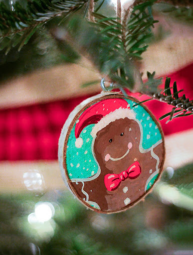 A gingerbread man ornament hanging from a christmas tree.