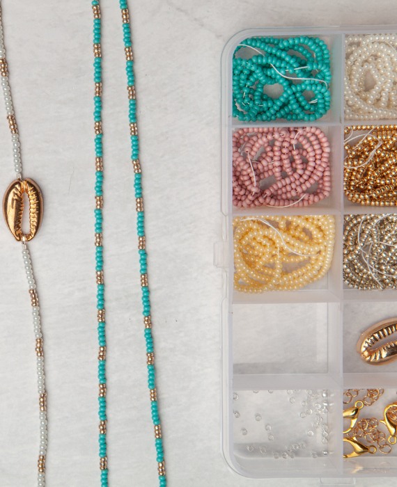 A box of beads and necklaces on a table.