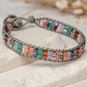 A bracelet with multi colored beads on top of a stone.