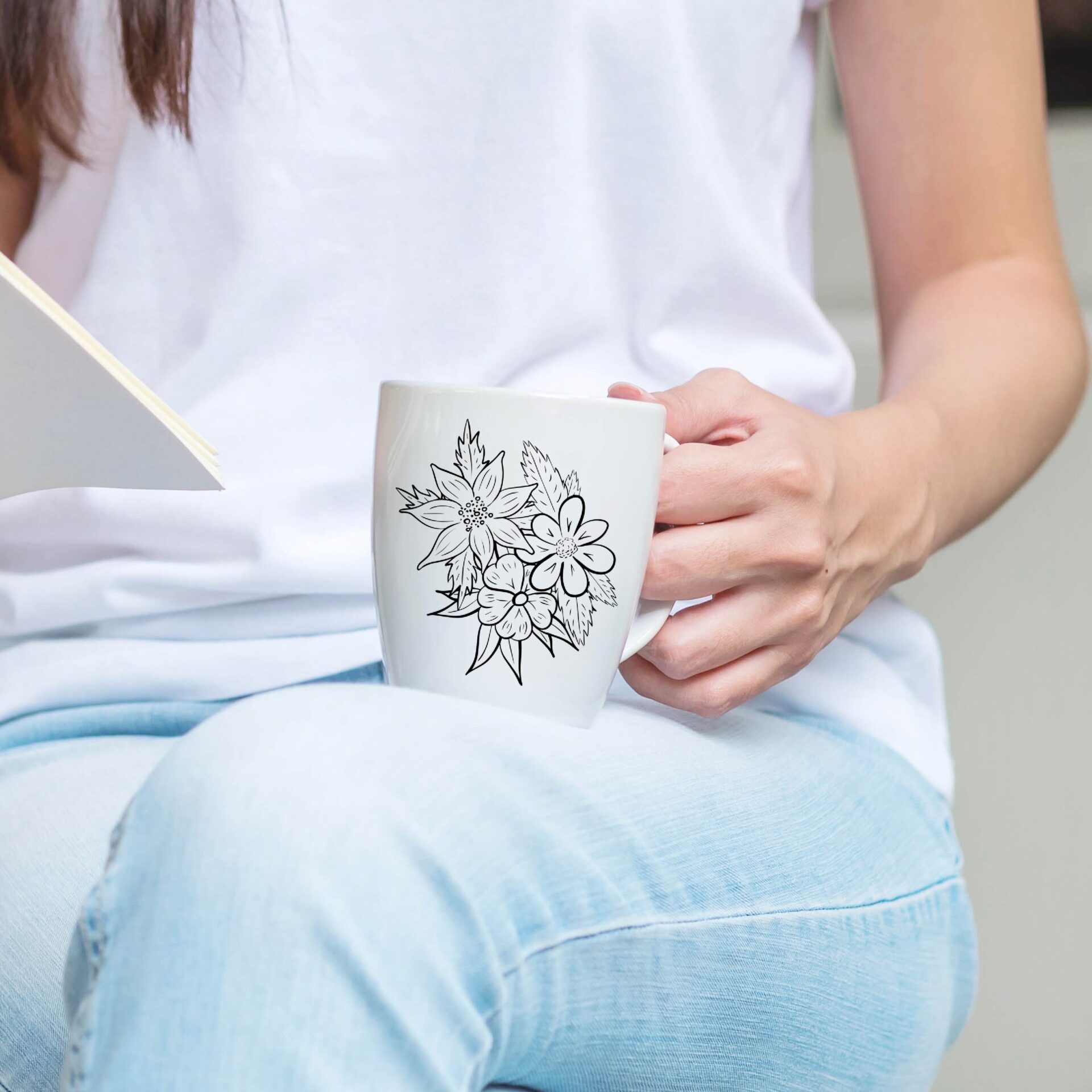 A woman holding a book and a mug.