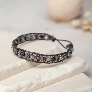 A bracelet with blue and brown beads on top of a stone.