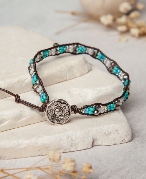 A bracelet with turquoise beads and a silver charm.