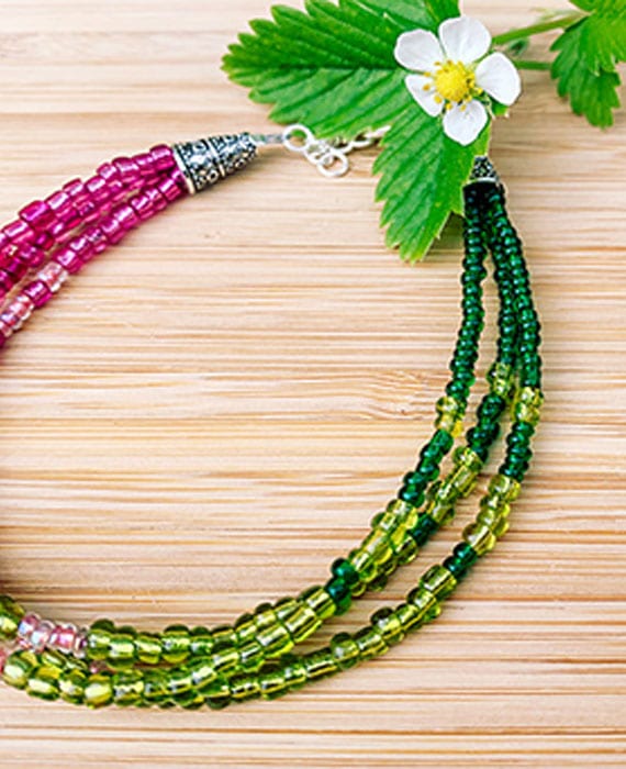 A necklace with green and pink beads and a flower.