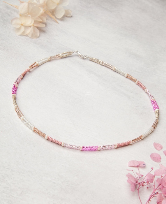 A pink and white beaded necklace on a white surface.