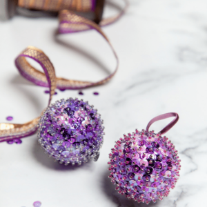 Two purple sequin ornaments on a marble table.