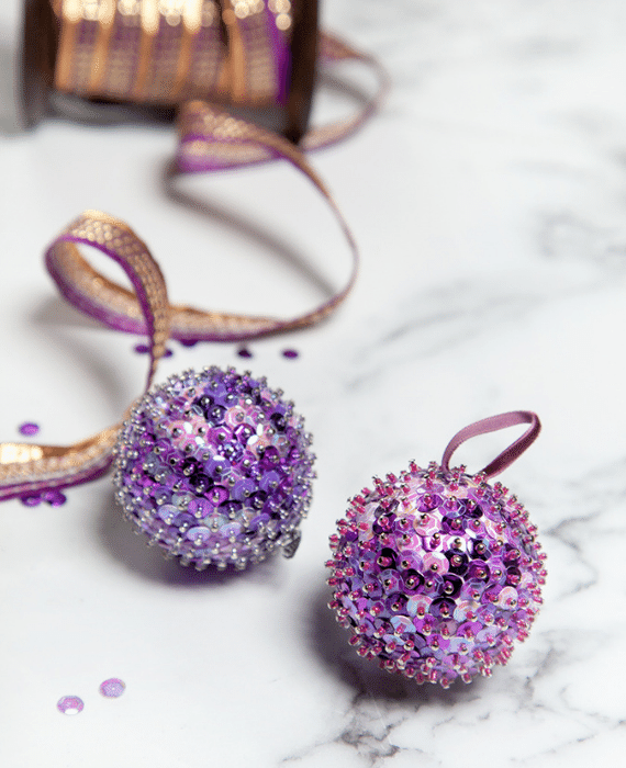 Two purple sequin ornaments on a marble table.