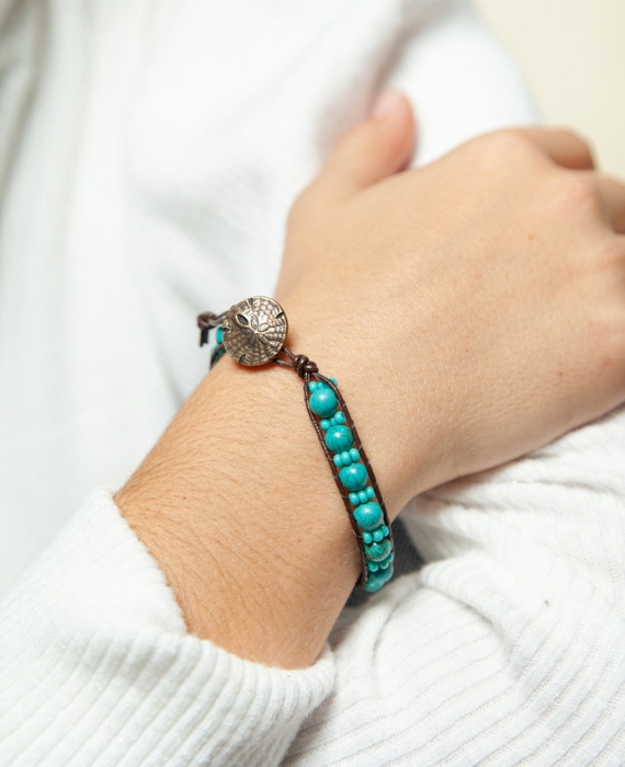 A woman's wrist with a turquoise beaded bracelet.