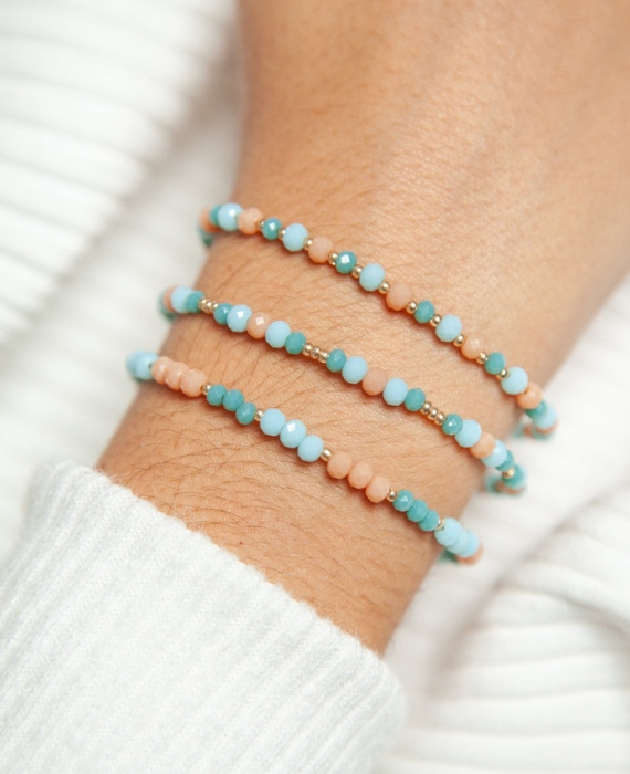 A woman's wrist with three beaded bracelets on it.