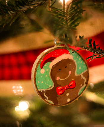 A gingerbread ornament hanging from a christmas tree.