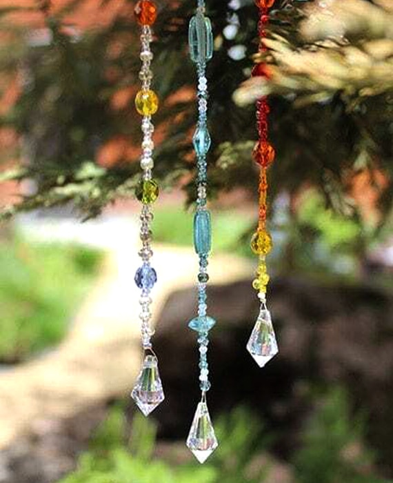 Three colorful glass beads hanging from a tree.