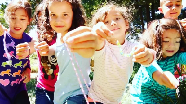 A group of children are holding Kids Jewelry Making Party - Bay Area in their hands.