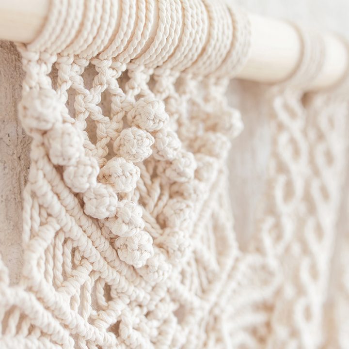 Close-up of hand made macrame texture pattern.  ECO friendly modern knitting DIY natural decoration concept  in the interior. Flat lay. Handmade macrame 100% cotton. Details close up. Female hobby.